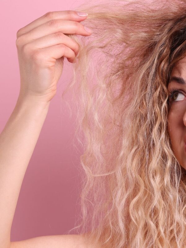 Woman looking confused at her hair, holding it up.