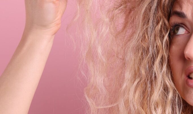 Woman looking confused at her hair, holding it up.