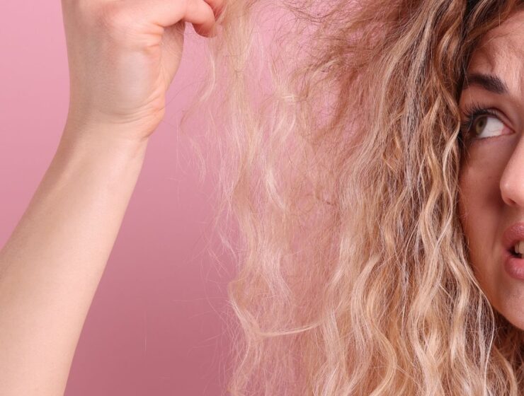 Woman looking confused at her hair, holding it up.