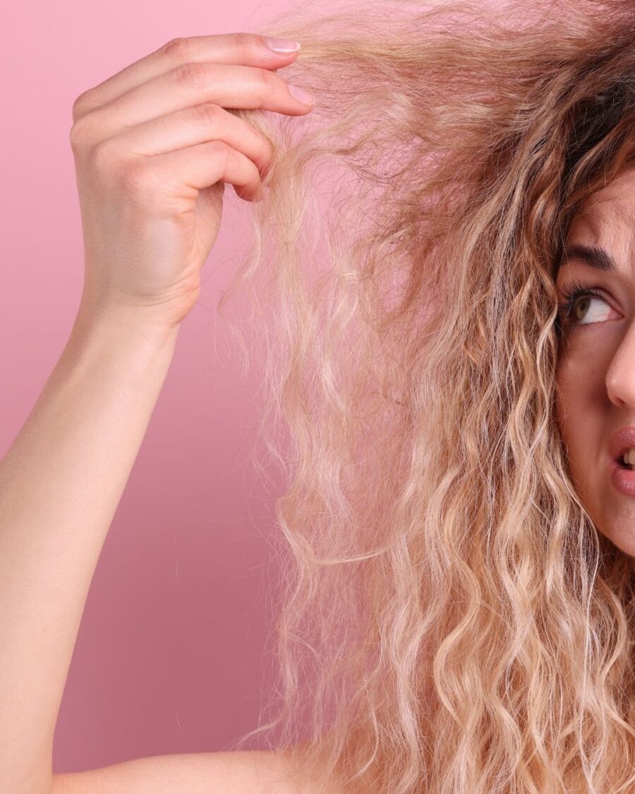 Woman looking confused at her hair, holding it up.