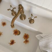 Bathroom sink with a gold faucet and handles.