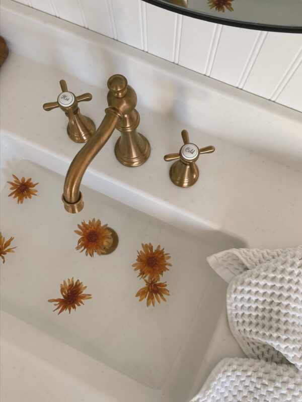 Bathroom sink with a gold faucet and handles.