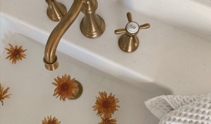 Bathroom sink with a gold faucet and handles.