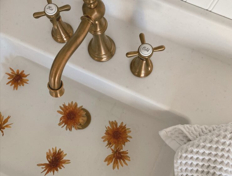 Bathroom sink with a gold faucet and handles.