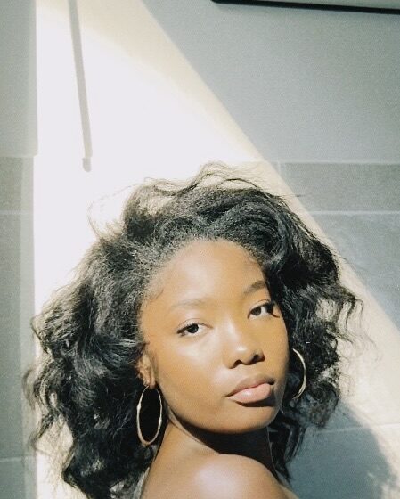 Woman with heat styled hair posing in soft sunlight.