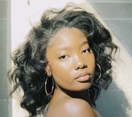 Woman with heat styled hair posing in soft sunlight.