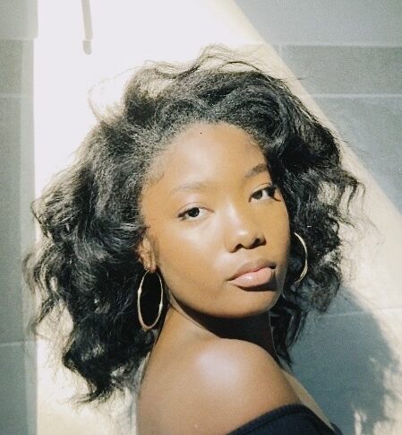 Woman with heat styled hair posing in soft sunlight.