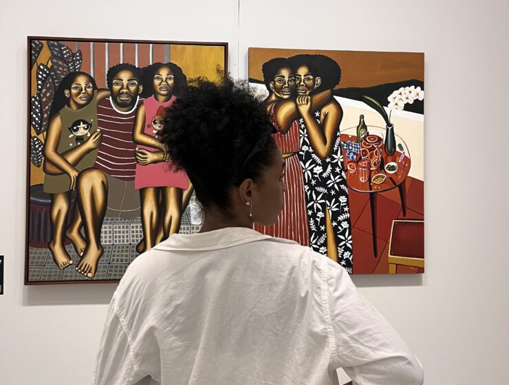 Woman with black curly hair tied up looking at art.