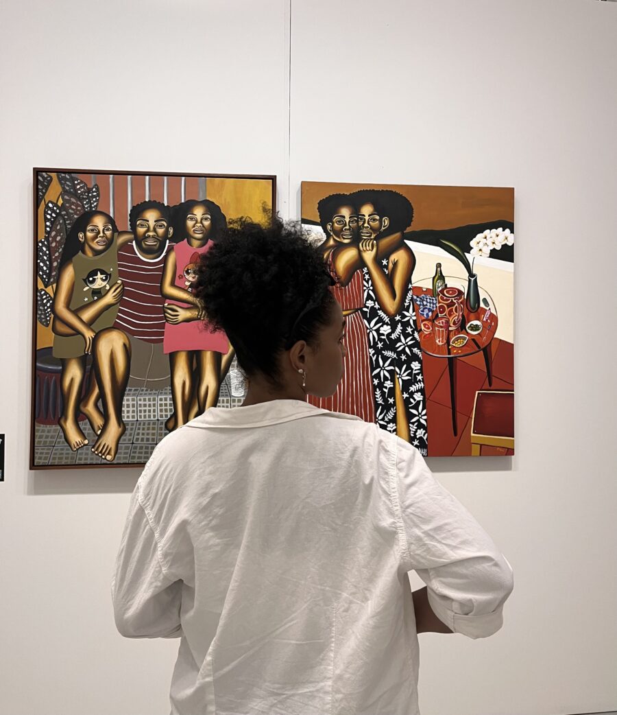 Woman with black curly hair tied up looking at art.