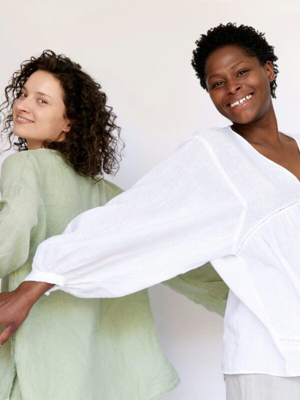 Two woman with curly hair posing for camera.