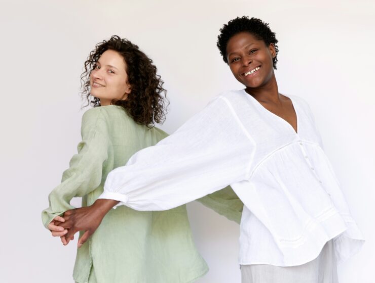Two woman with curly hair posing for camera.