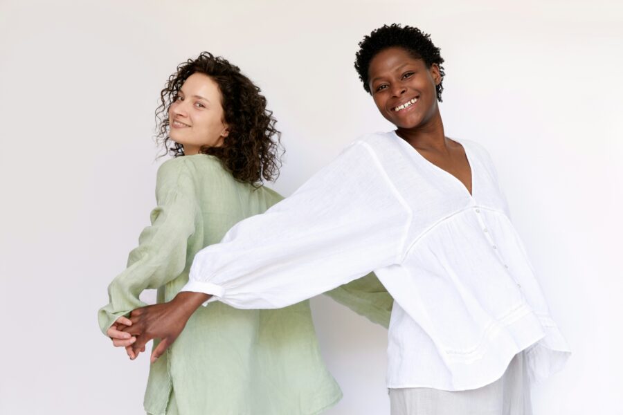 Two woman with curly hair posing for camera.