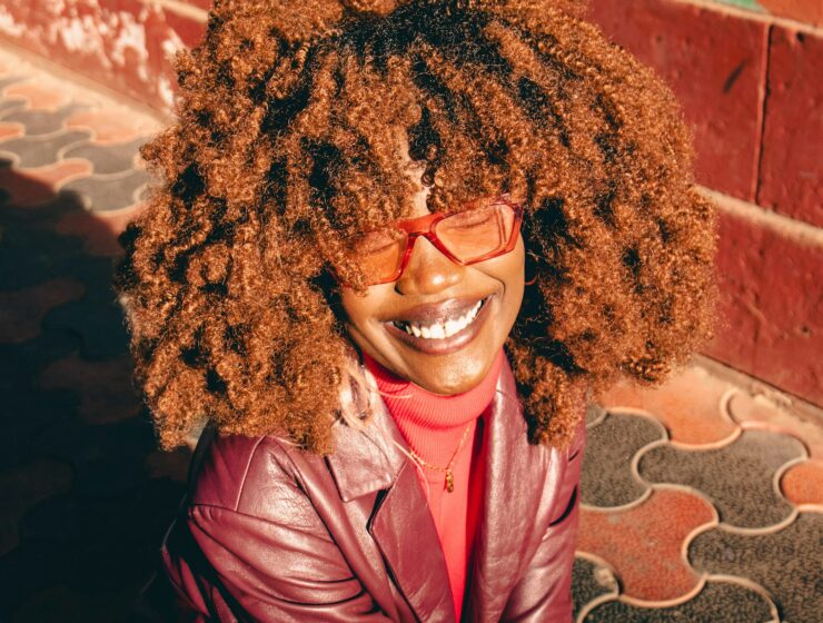 Woman with red curly hair, red glasses and a red jacket.