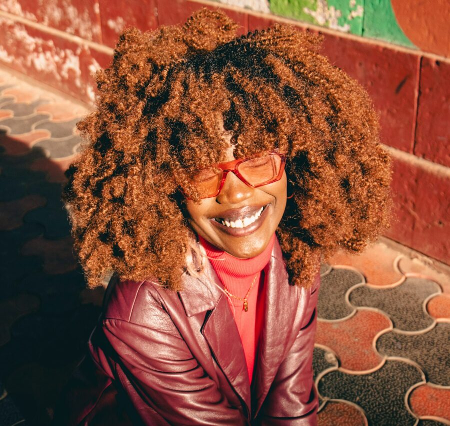 Woman with red curly hair, red glasses and a red jacket.
