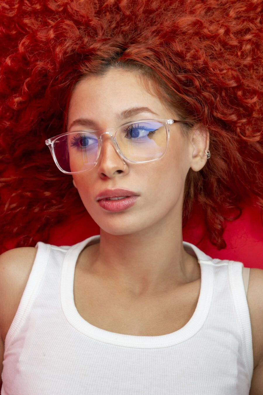 Close up of a woman with red curly hair wearing glasses.