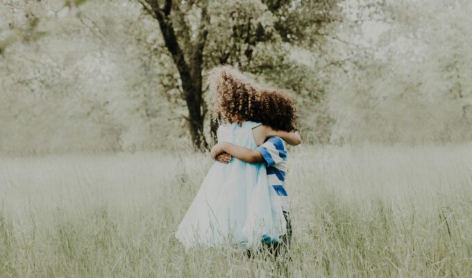 Two children with curly hair hugging
