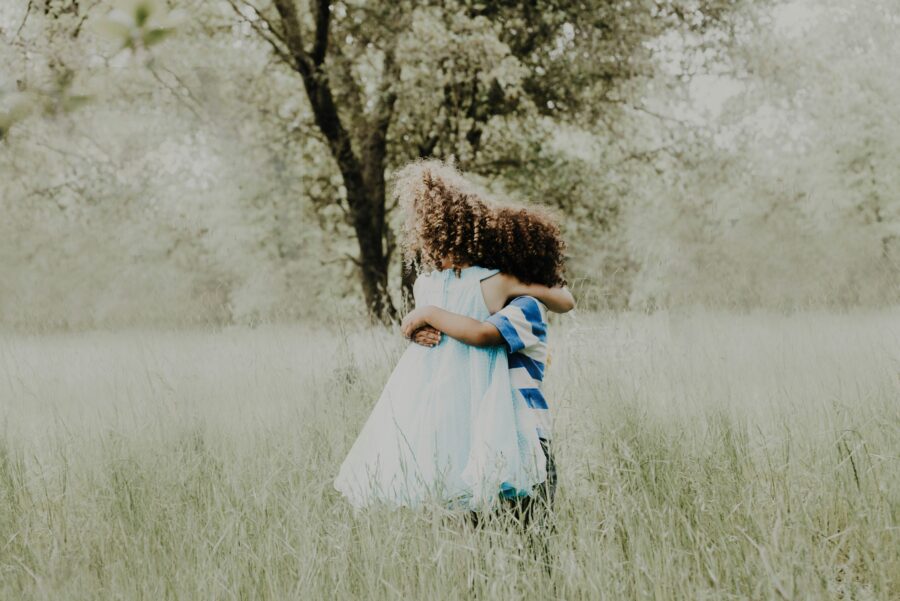 Two children with curly hair hugging