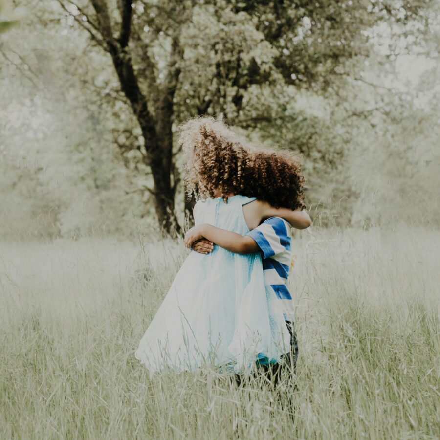 Two children with curly hair hugging
