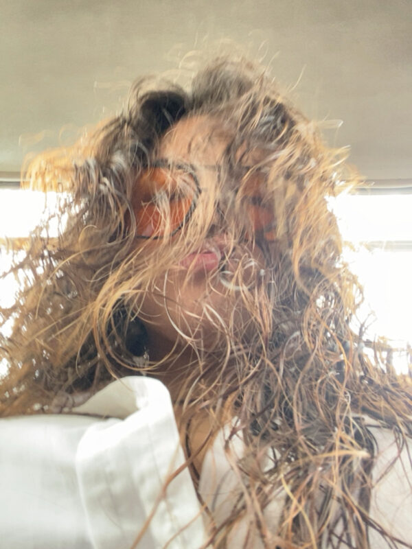 Woman taking a selfie with curly hair.