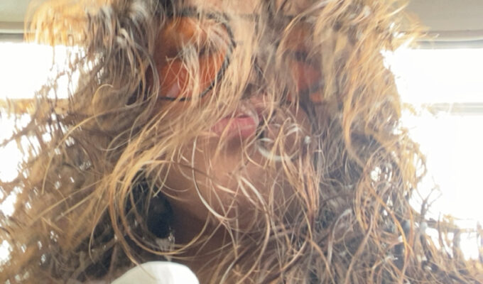 Woman taking a selfie with curly hair.