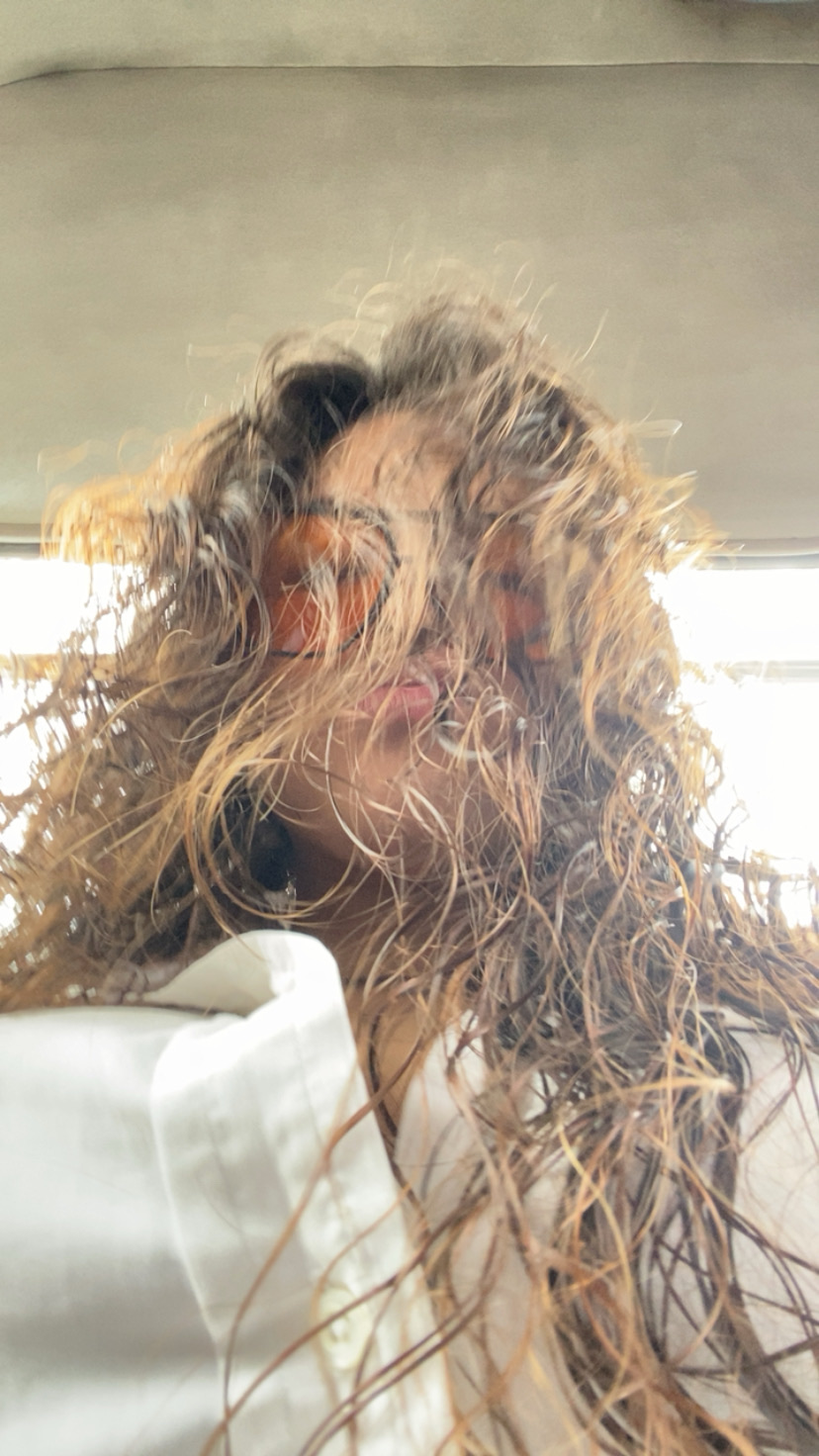 Woman taking a selfie with curly hair.
