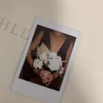 Woman holding flowers in a polaroid photo.