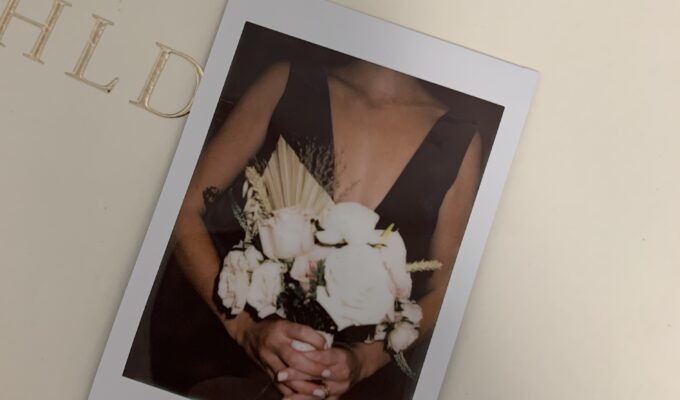 Woman holding flowers in a polaroid photo.