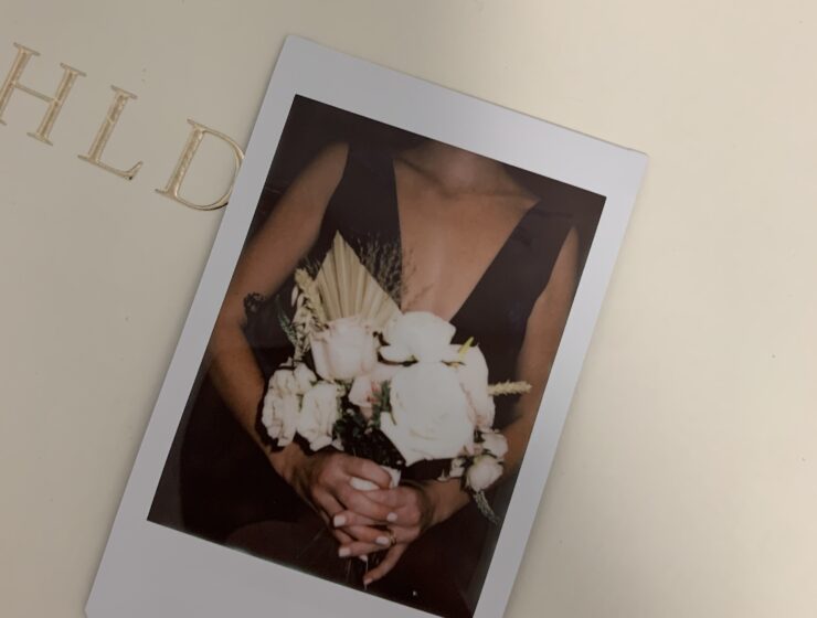 Woman holding flowers in a polaroid photo.