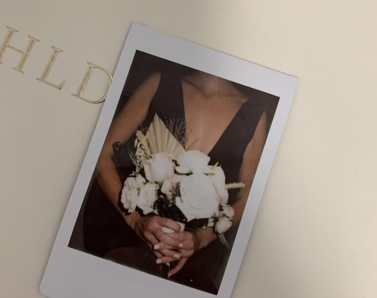 Woman holding flowers in a polaroid photo.
