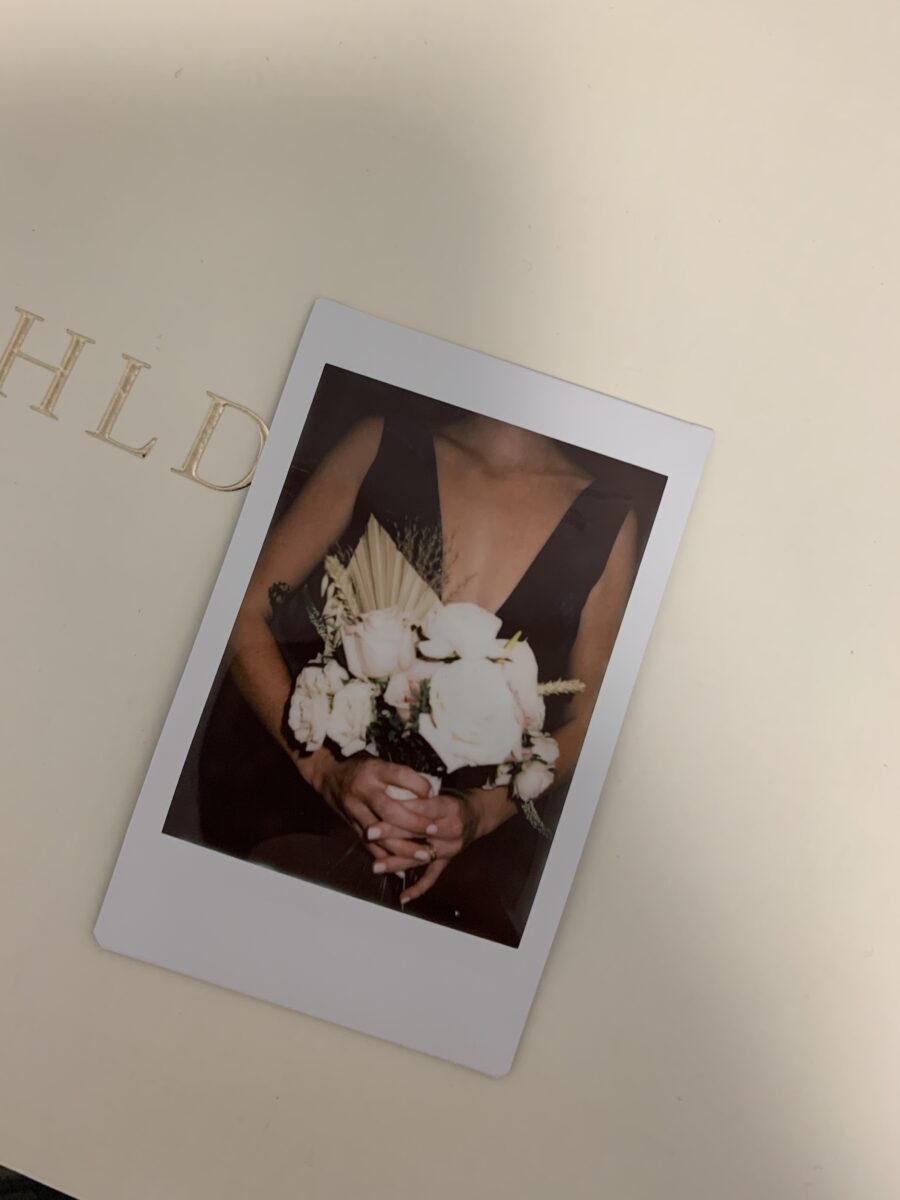 Woman holding flowers in a polaroid photo.