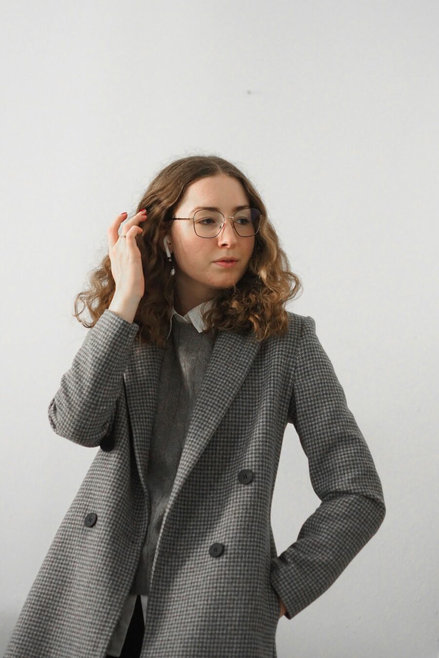 Woman posing, with hand pushing hair slightly back.