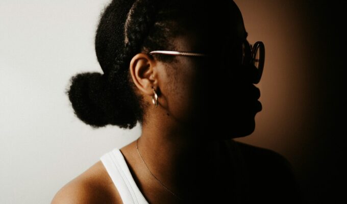 Woman side profile wearing her curly hair in a low bun.