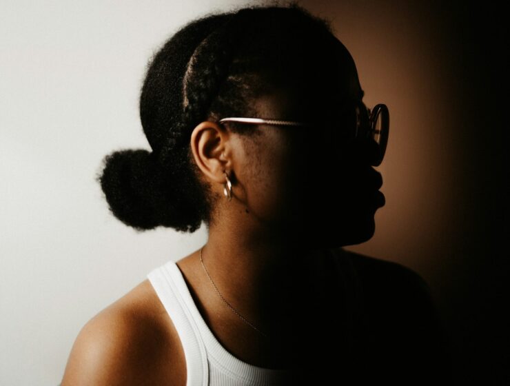Woman side profile wearing her curly hair in a low bun.