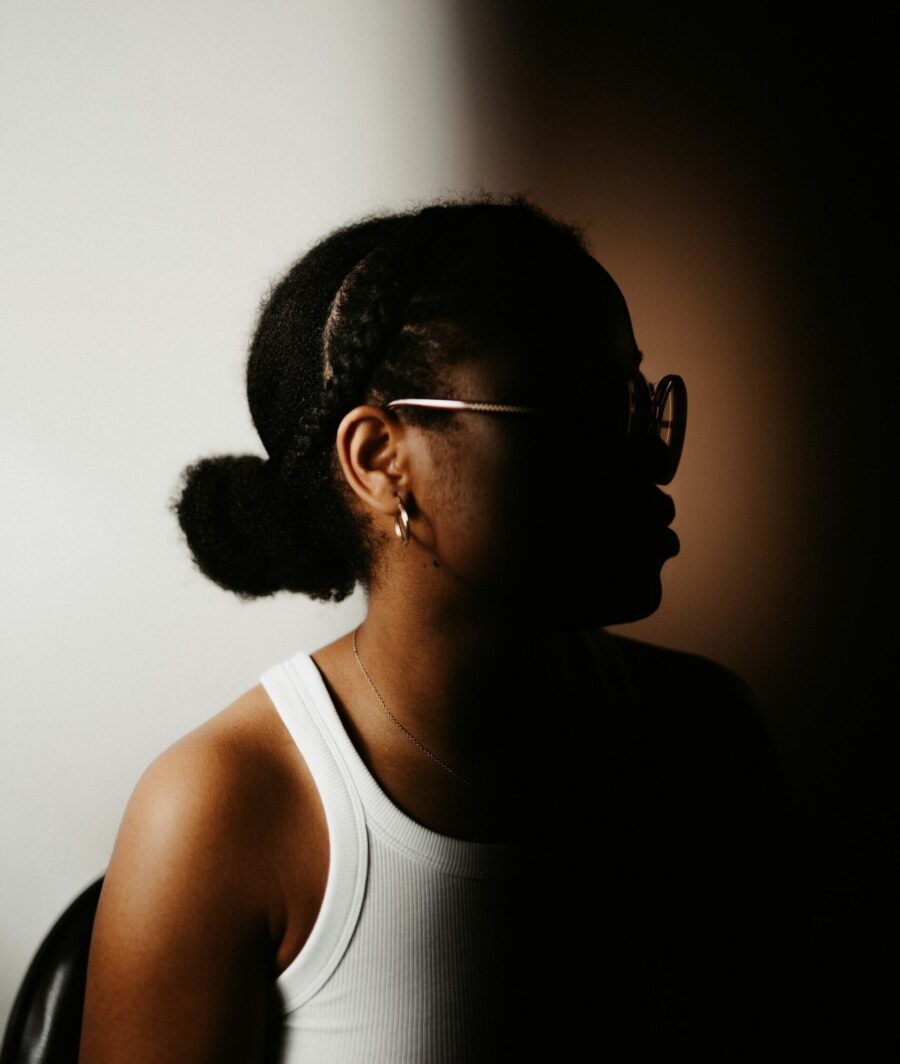 Woman side profile wearing her curly hair in a low bun.