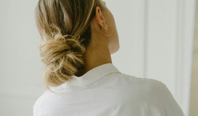 Back of womans head with her hair tied up in a low ponytail.