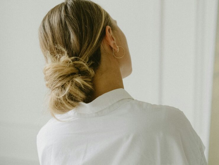 Back of womans head with her hair tied up in a low ponytail.