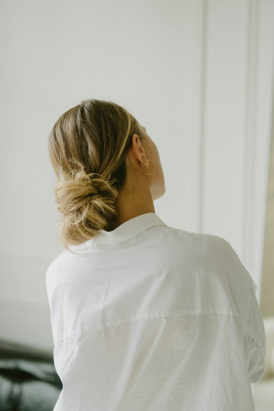 Back of womans head with her hair tied up in a low ponytail.