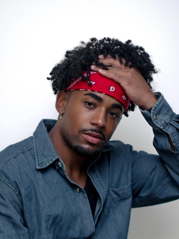 Man with curly hair wearing a fashion red bandana.