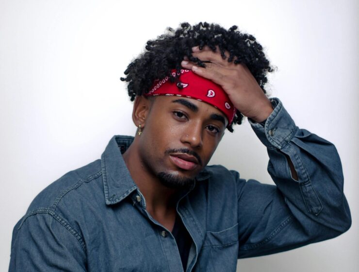 Man with curly hair wearing a fashion red bandana.