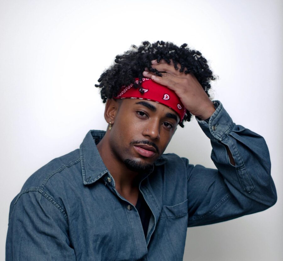 Man with curly hair wearing a fashion red bandana.