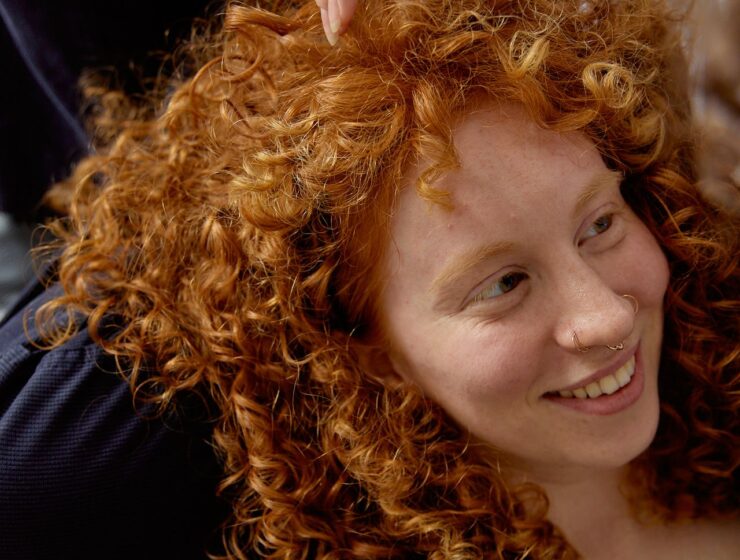 Woman with curly hair sitting on a chair.