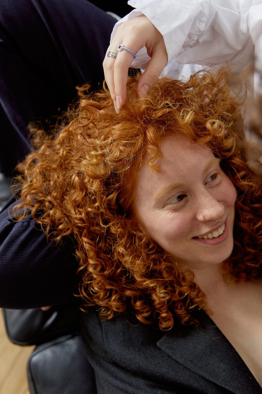 Woman with curly hair sitting on a chair.
