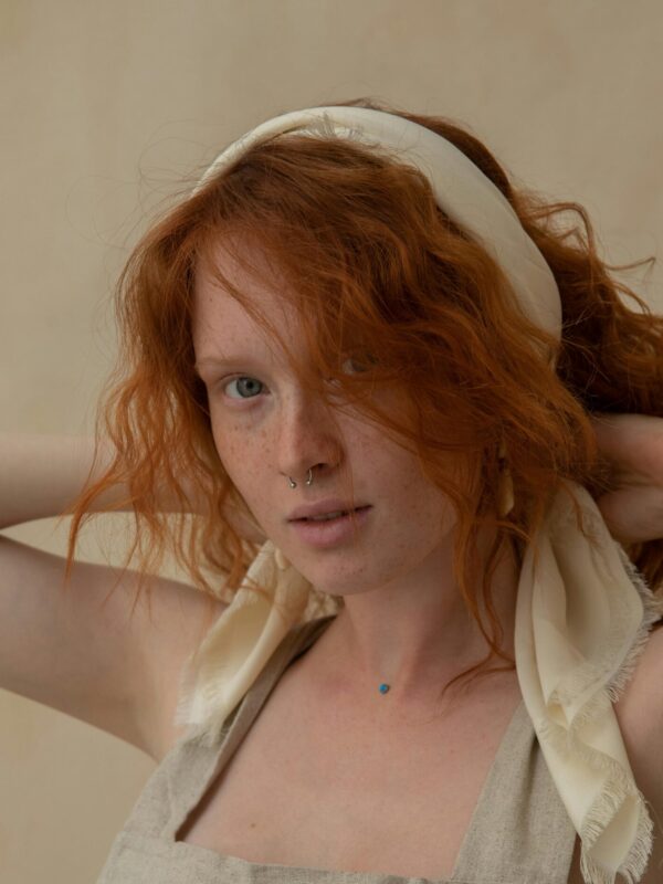 Woman with red hair wearing a hair accessory.