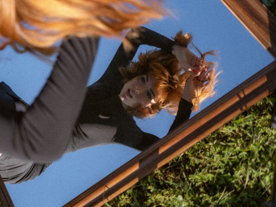 Woman looking in the mirror, where the mirror is placed on the ground.