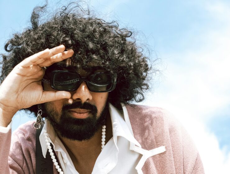 Man with big curly hair wearing sunglasses.
