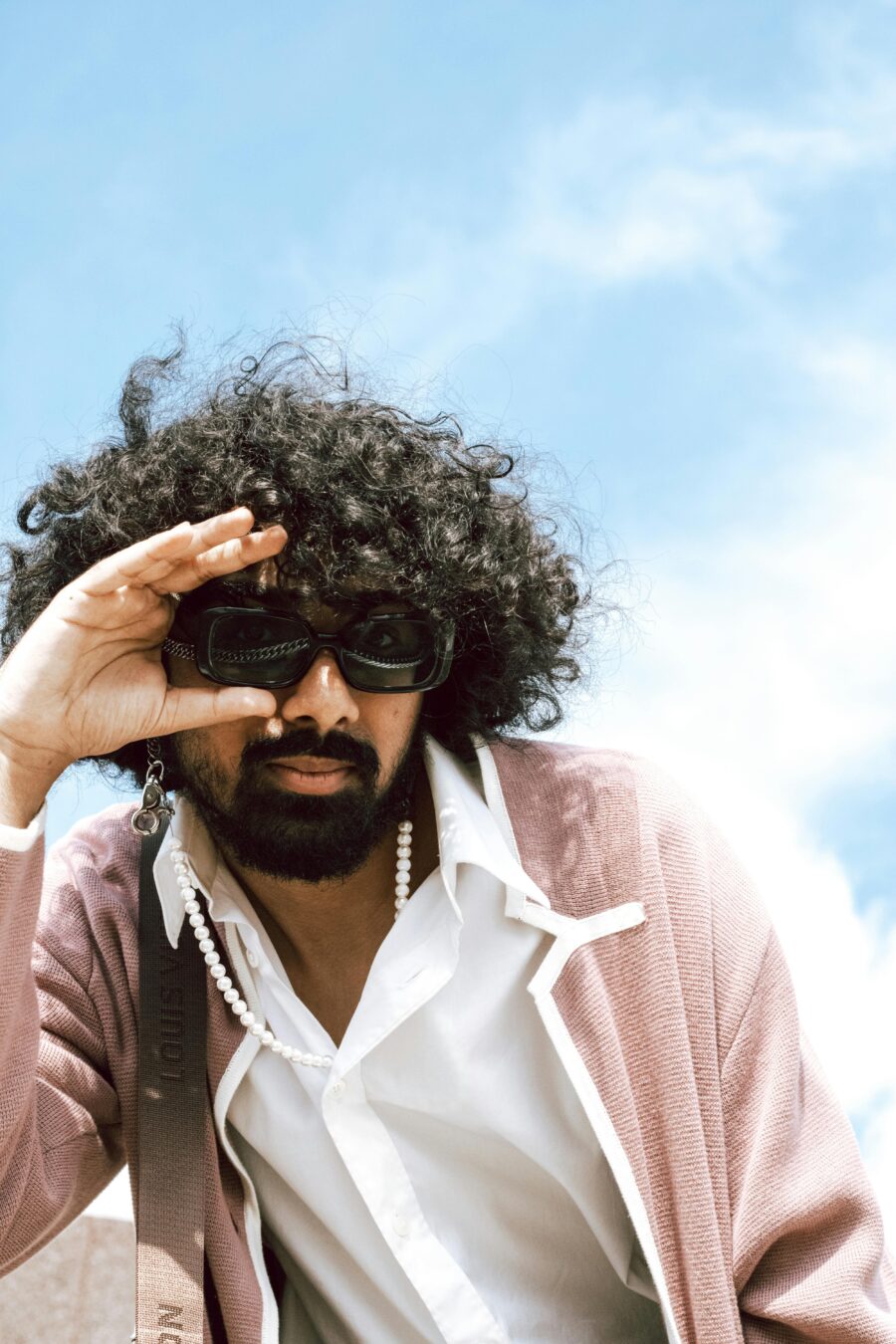 Man with big curly hair wearing sunglasses.