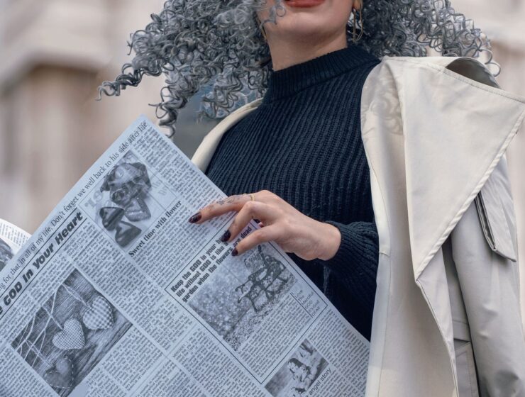 Woman with grey hair, holding a newspaper.