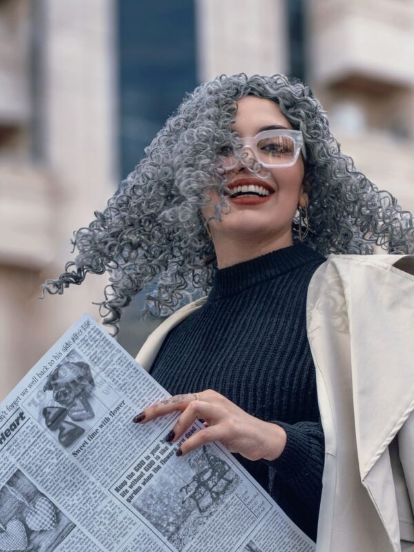 Woman with grey hair, holding a newspaper.