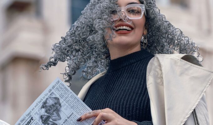Woman with grey hair, holding a newspaper.