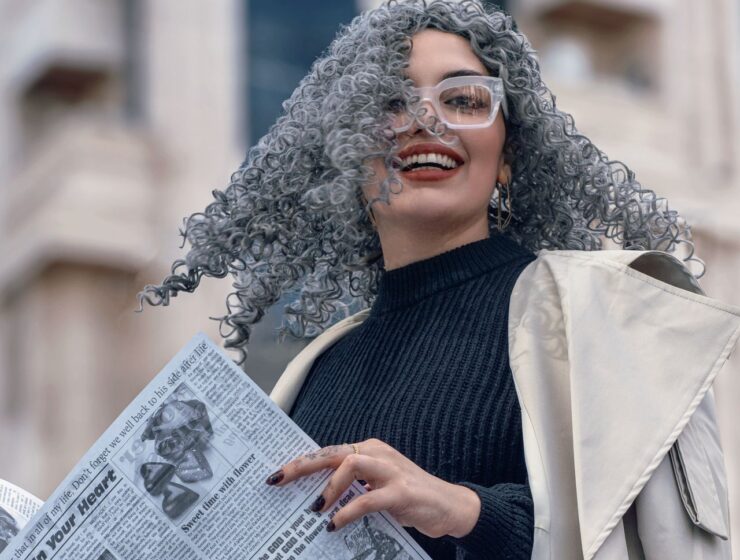Woman with grey hair, holding a newspaper.